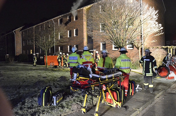 Dramatische Situation beim Eintreffen der Feuerwehr: Ein Frau sitzt außen auf dem Fensterbett ihrer brennenden Wohnung. Die Feuerwehr bringt ein Sprungpolster in Stellung. Foto: Preuschoff