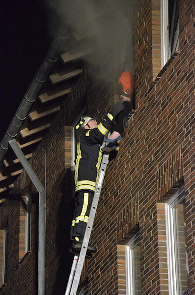 Ein Feuerwehrmann betreut die Frau von außen, während der Angriffstrupp ihr eine Fluchthaube aufsetzt. Foto: Preuschoff