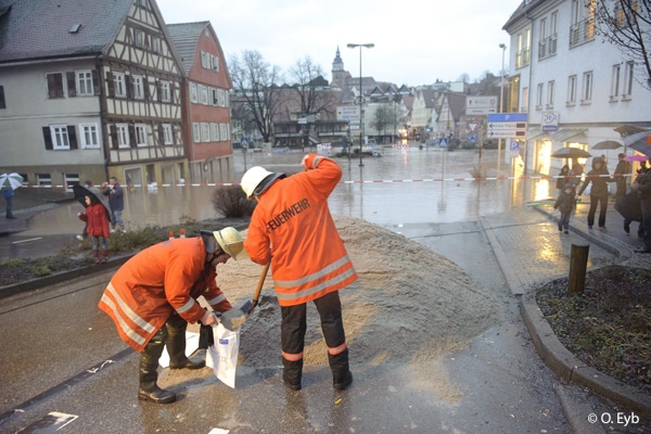 Hochwasser in Backnang, ein Laster kippte zwei Ladungen Sand in die Asbach (oder so ähnlich) Strasse, Feuerwehrleute befuellten Sandsäcke damit