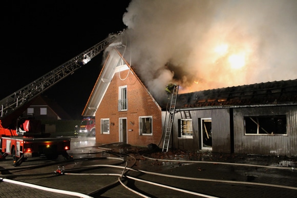 Flammen treten aus dem Dachstuhl eines Wohnhauses aus. Autohaus -Brand in Twistringen. Foto: Kreisfeuerwehr Diepholz / Thom