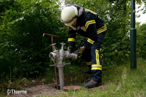 Ein Feuerwehrmann bringt an einem Standrohr einen Systemtrenner BA an. Foto: Thieme