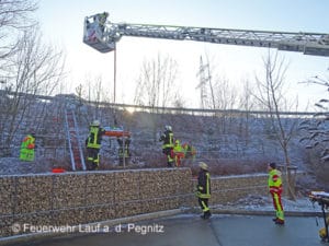 Per Drehleiter und Schleifkorbtrage rettet die Feuerwehr Lauf a. d. Pegnitz einen flüchtigen Fahrer, der verletzt hinter einem Zaun liegt. Foto: Feuerwehr Lauf a. d. Pegnitz