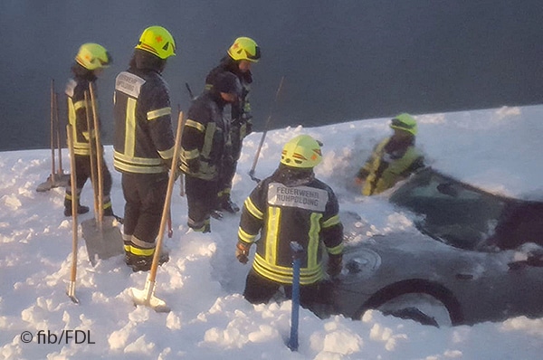 Feuerwehrleute im Schnee mit Pkw