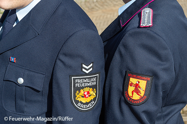 Zwei Feuerwehrleute aus Bremen und Niedersachsen stehen nebeneinander.