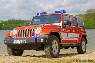 Ein Jeep der Feuerwehr Neckartailfingen steht am Strand eines Badeseesteht