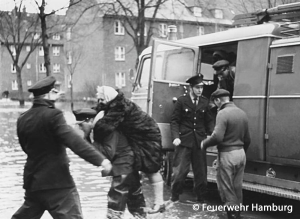 Feuerwehrleute helfen geretteten Menschen aus einem Löschfahrzeug