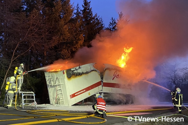 Unter anderem über eine Lkw-Rettungsbühne löschen Feuerwehrleute einen mit Elektroschrott beladenen Sattelauflieger an der A 7. Durch das Feuer ist er auseinandergebrochen.