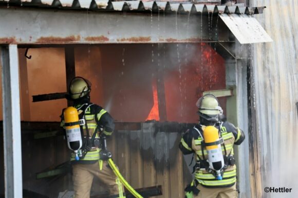 Ein Angriffstrupp bekämpft die Flammen an der brennenden Lagerhalle. Foto: Hettler