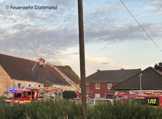 Bei dem Scheunenbrand in Dortmund-Scharnhorst zieht heißer Brandrauch ins Dachgeschoss. Ein Trupp kontrolliert unter Atemschutz von einer Drehleiter aus das Gebäude und entfernt die Dachpfannen. Foto: Feuerwehr Dortmund
