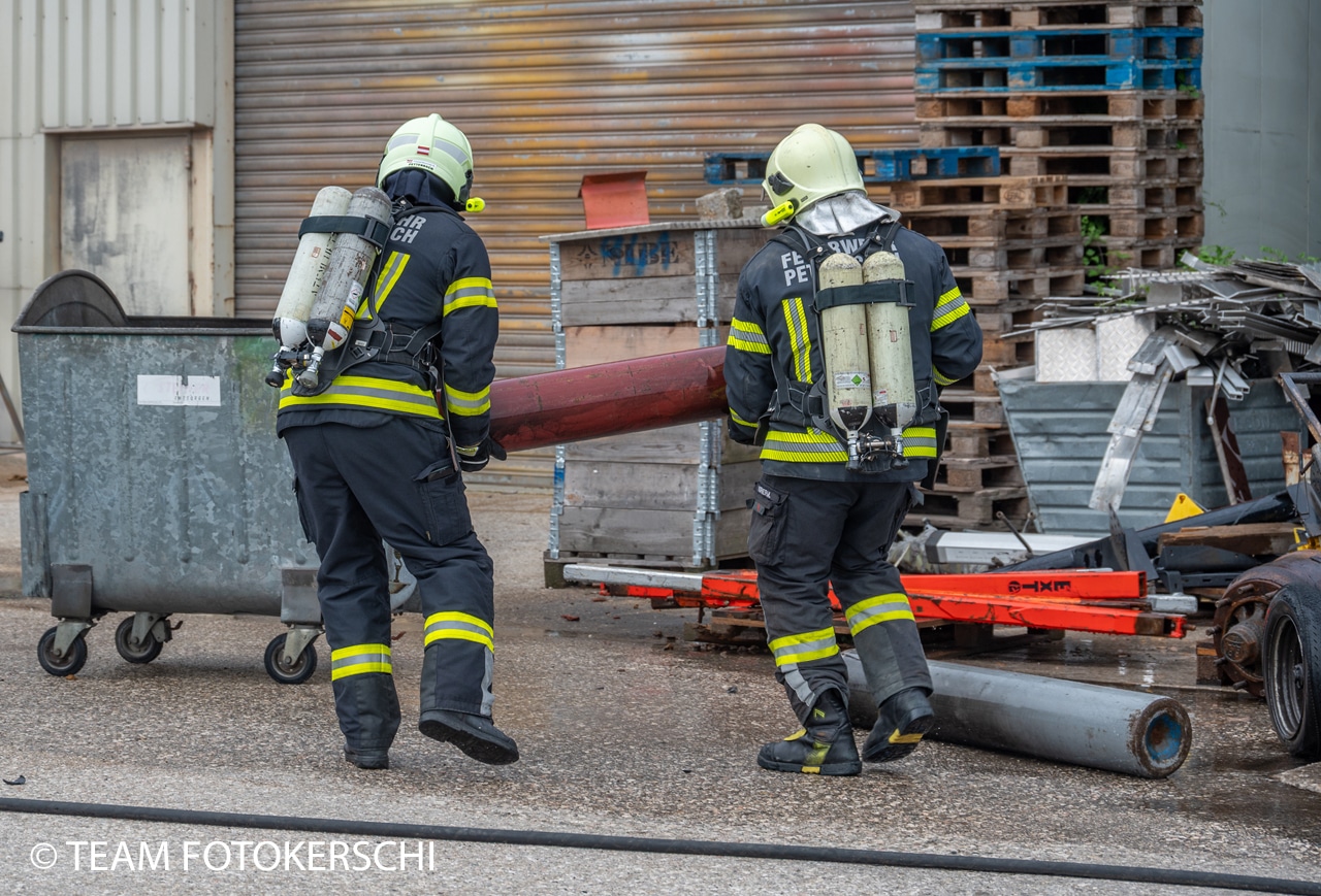Zur endgültigen Abkühlung bringen Feuerwehrkräfte ausgebrannte Gasflaschen in einen mit Wasser gefüllten Container. Foto: TEAM FOTOKERSCHI