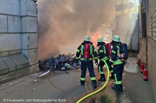 Feuerwehrkräfte gehen unter Atemschutz gegen den Brand eines Recyclinghaufens vor.