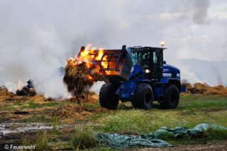 Radlader transportiert brennendes Stroh