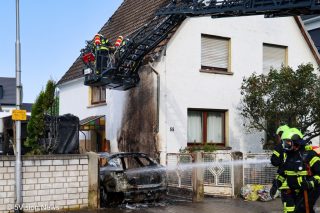 Drehleiterkorb vor Haus über ausgebranntem Pkw