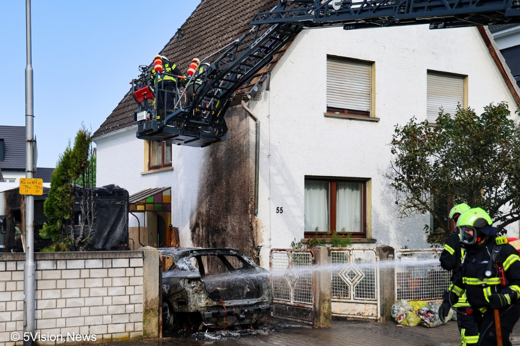 Drehleiterkorb vor Haus über ausgebranntem Pkw