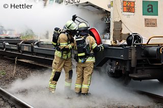 Eine weiße Wolke unter einem Kesselwagen sorgt für einen Gefahrguteinsatz der Feuerwehr in Aschaffenburg. Die Kräfte nähern sich unter Atemschutz dem Waggon. Foto: Hettler