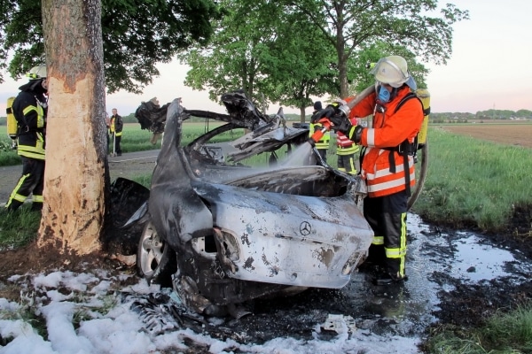Feuerwehrleute löschen das ausgebrannte Heck eines Mercedes-CLK ab. In dem Wrack starben zwei junge Männer. (Fotos: Polizei)