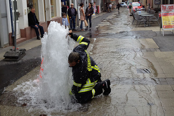 Nach einem Unfall strömt aus einem Unterflurhydranten in Weinheim Wasser aus. Ein Feuerwehrmann versucht vergeblich, den Hydranten zu schließen. Foto: Mittelbach/Feuerwehr