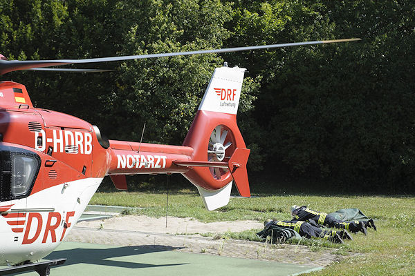 Start eines Rettungshubschraubers in Stuttgart: zwei Feuerwehrleute sichern vorsorglich eine Abdeckplane, damit diese nicht aufgewirbelt wird. Foto: 7aktuell.de/Eyb