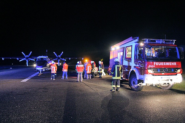 Feuerwehrkräfte stehen am Flugplatz neben der notgelandeten Dornier DO-228. Foto: Stürenburg/Feuerwehr