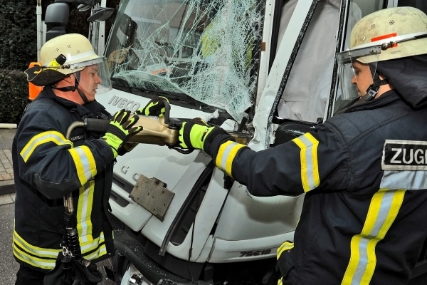 Mitglieder der Feuerwehr Nordhorn entfernen mit einem Spreizer die Fahrertür eines verunfallten Lkw. Anschließend kann der eingeklemmte Fahrer befreit werden. (Foto: Stepahn Konjer)